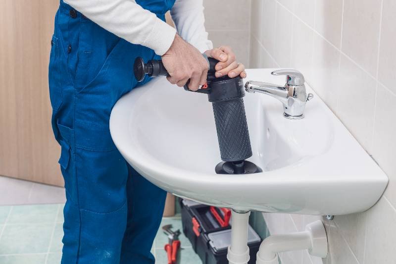 Plombier utilisant une ventouse sur un lavabo