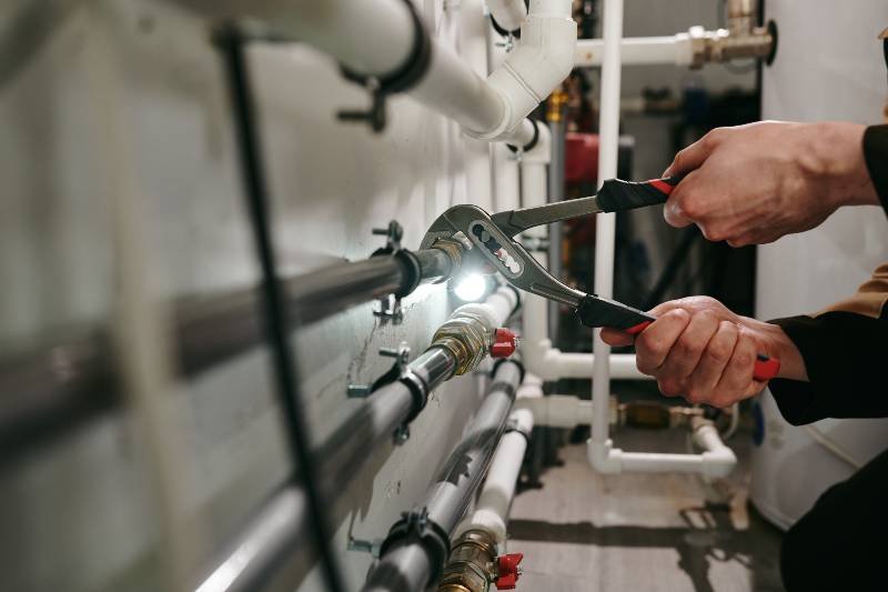 Mains d’un plombier travaillant sur des tuyauteries